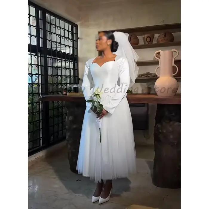 Robe de mariée mi-longue en tulle avec corsage en corset, manches longues évasées et basque, style p