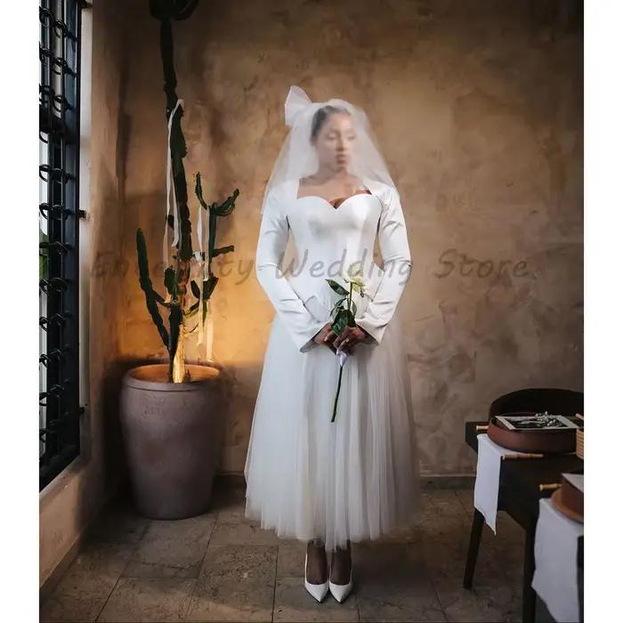 Robe de mariée mi-longue en tulle avec corsage en corset, manches longues évasées et basque, style petite robe de mariée
