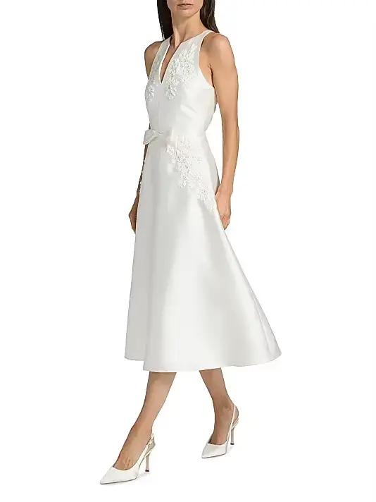 Robe de cocktail midi élégante et minimaliste en satin blanc, personnalisée, sans manches, avec encolure halter et appliques florales verticales en dentelle.