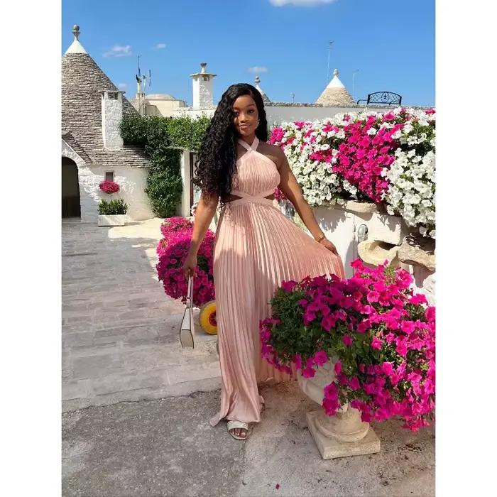 Robe longue plissée rose poudré en satin pour femme, style africain élégant, avec découpes à la taille, sans manches, pour soirée ou événement.