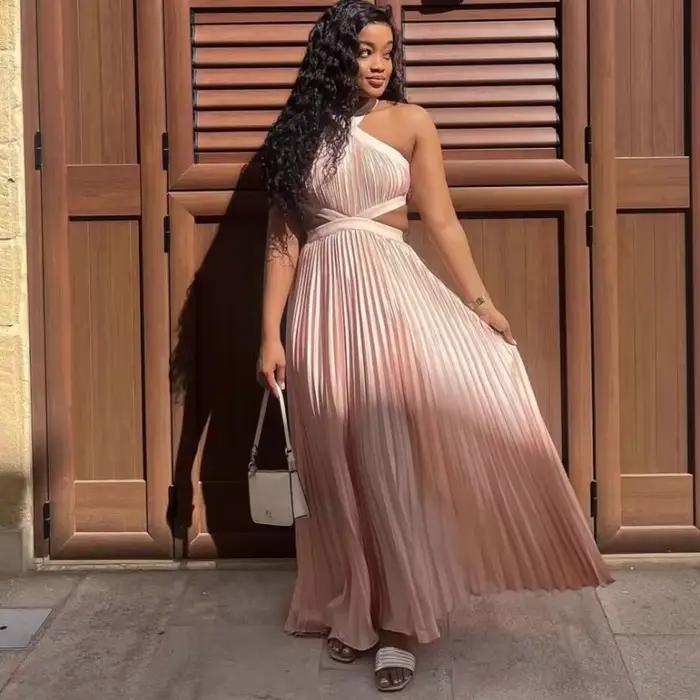 Robe longue plissée rose poudré en satin pour femme, style africain élégant, avec découpes à la taille, sans manches, pour soirée ou événement.