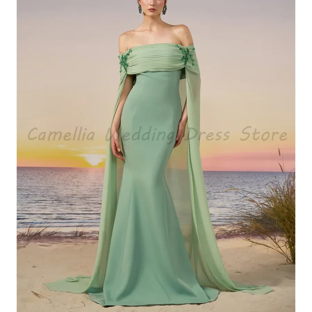 Robe de soirée longue vert sauge modeste à manches cape, épaules dénudées, froncée, perlée, coupe si