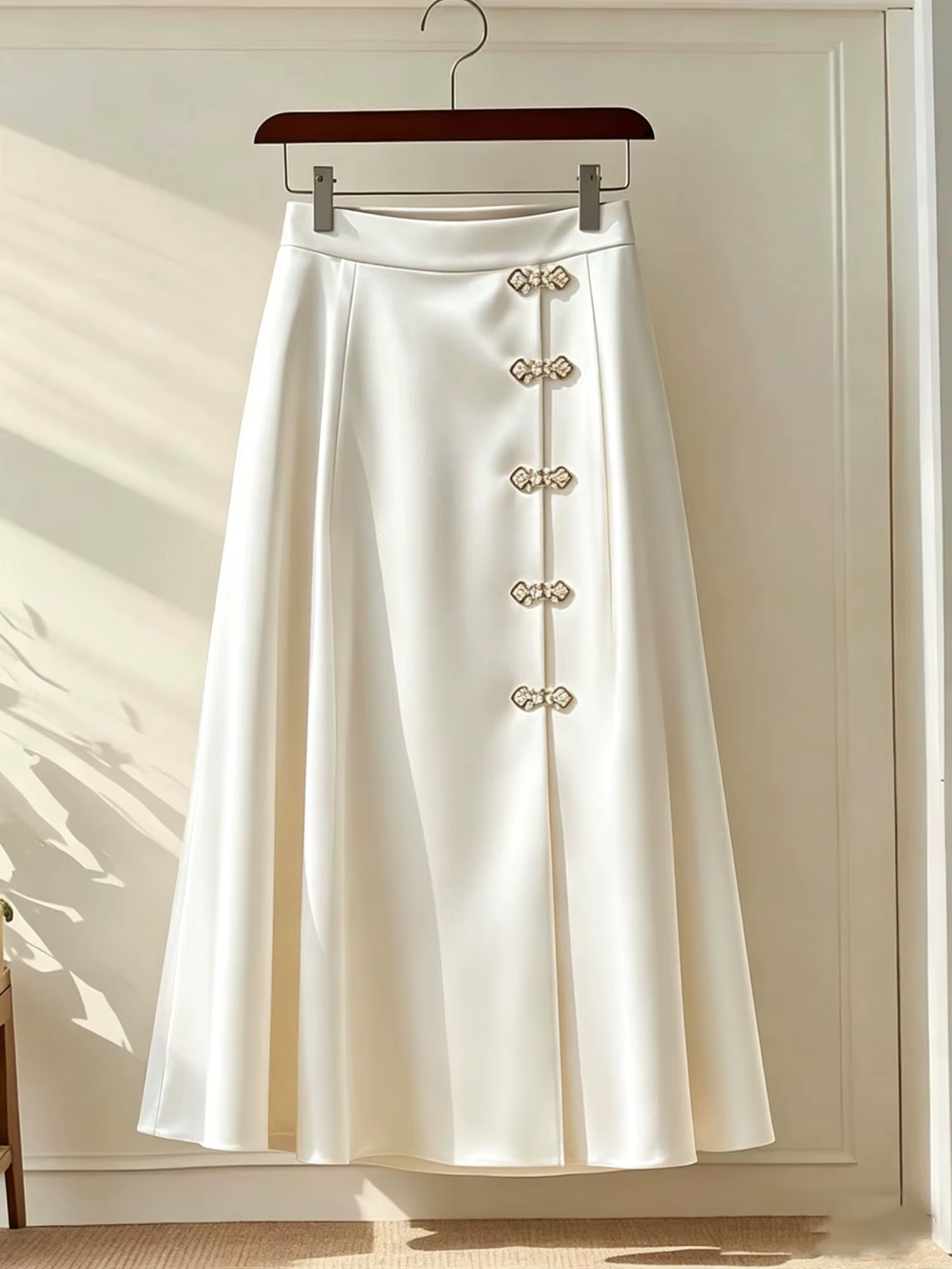 Jupe mi-longue évasée en satin brillant ivoire, taille haute, avec boutons grenouillère chinois en s